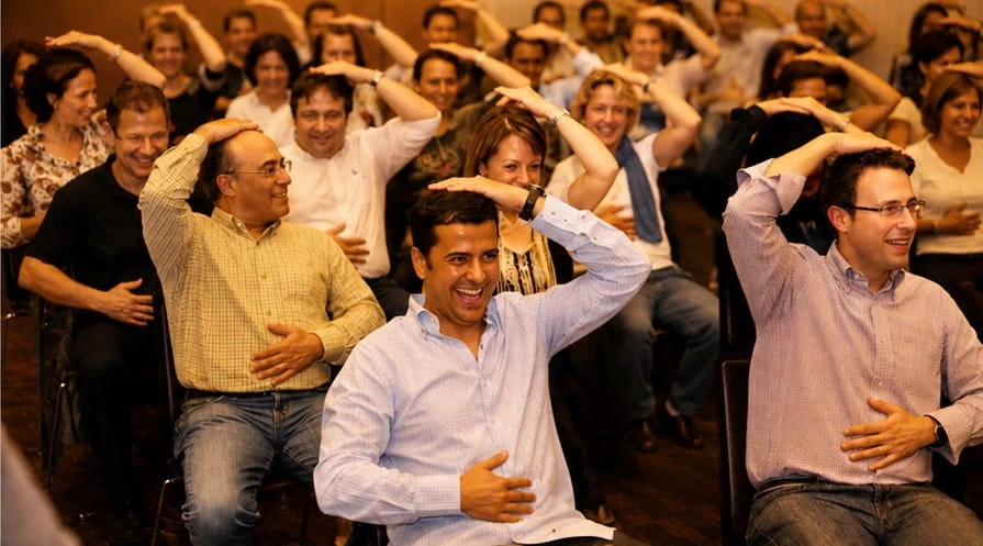 Grupo de una empresa riendo mientras realiza un ejercicio de coordinación corporal en un taller de Percumusic